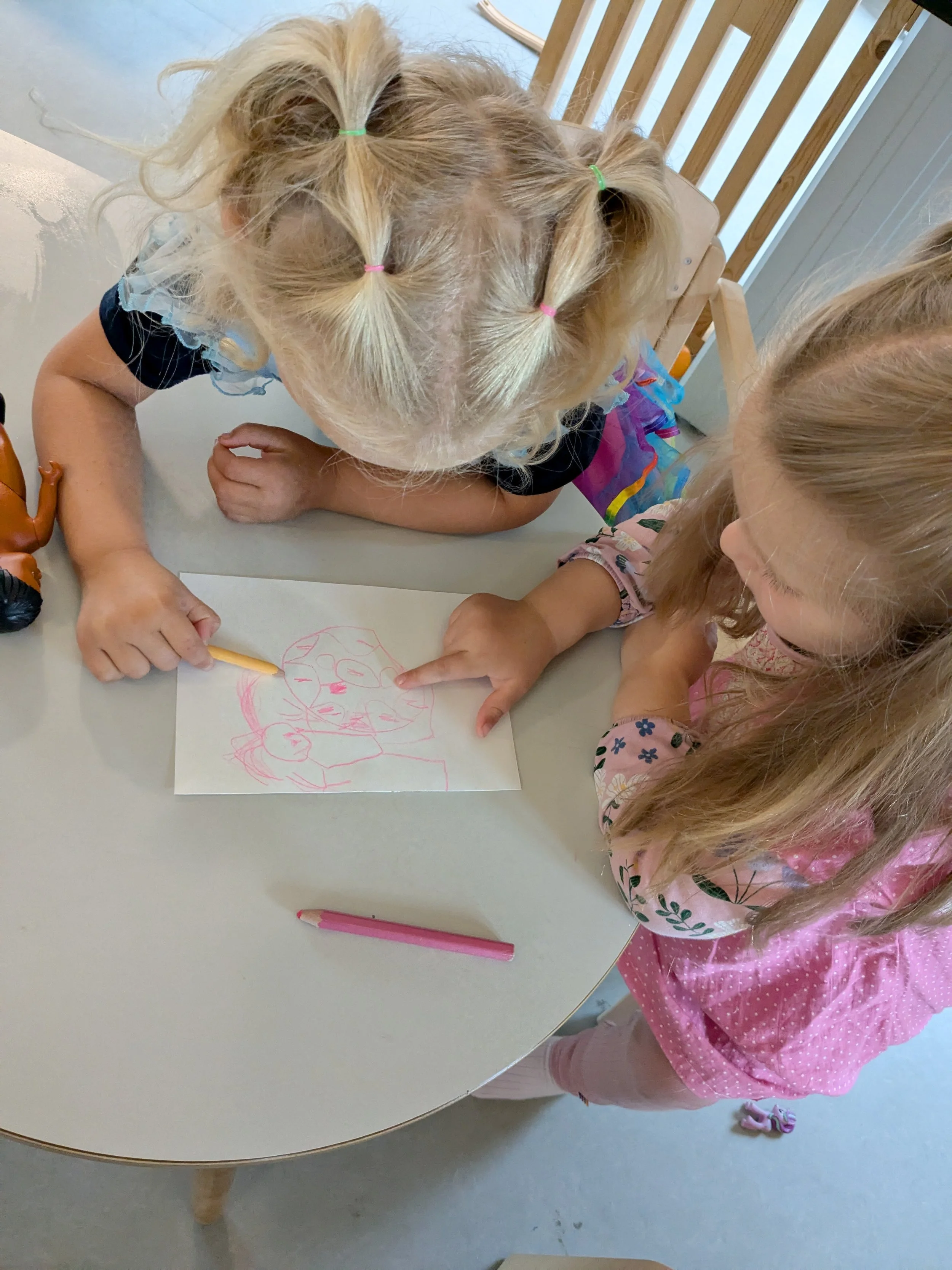 To barn tegner på en hvit ark med rosa farge