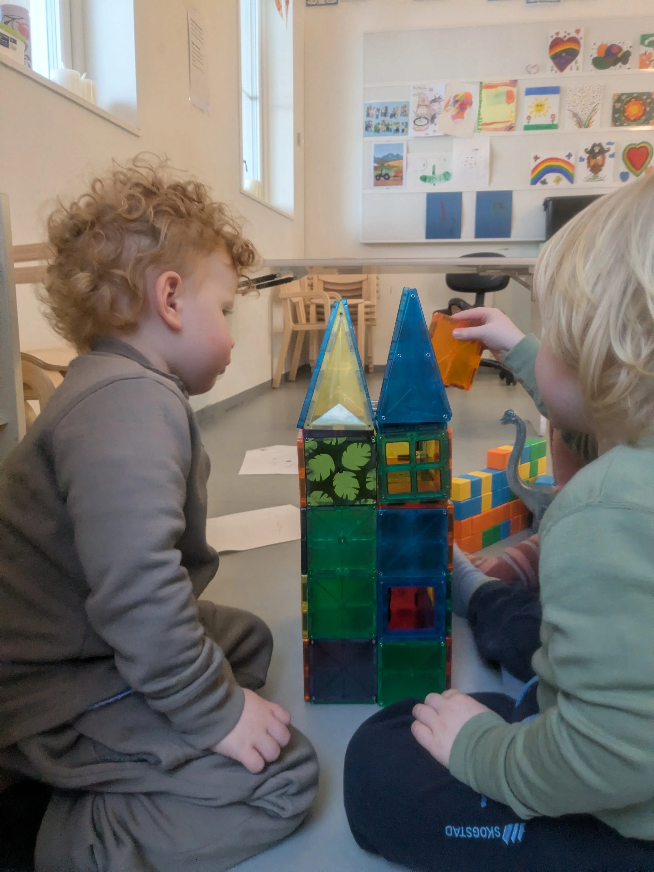 To barn som leker med fargede magneter og plastblokker.