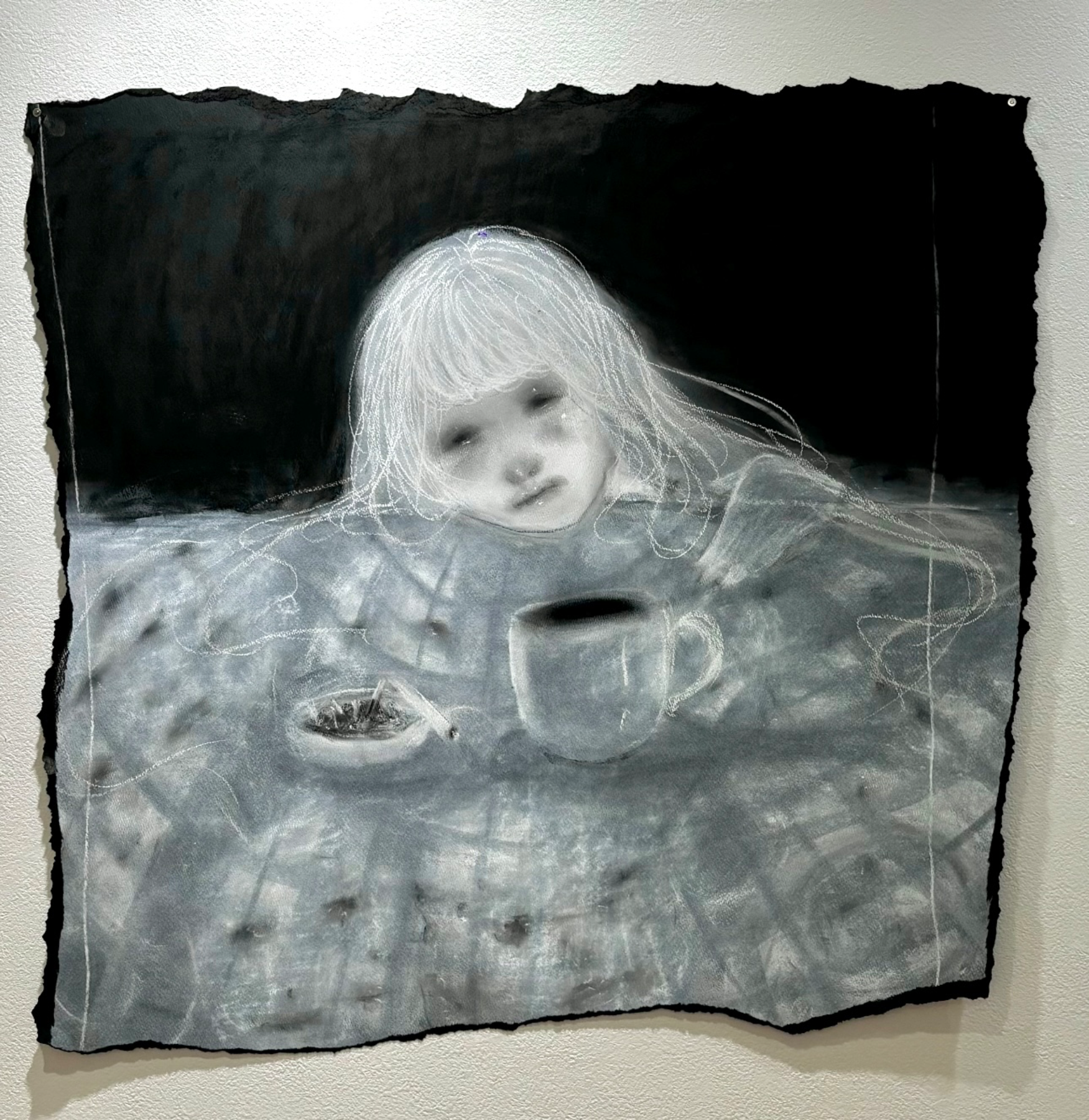 Artistic black-and-white drawing of a young girl with light hair, resting her head on a table with a mug and an ashtray, with a dark background.