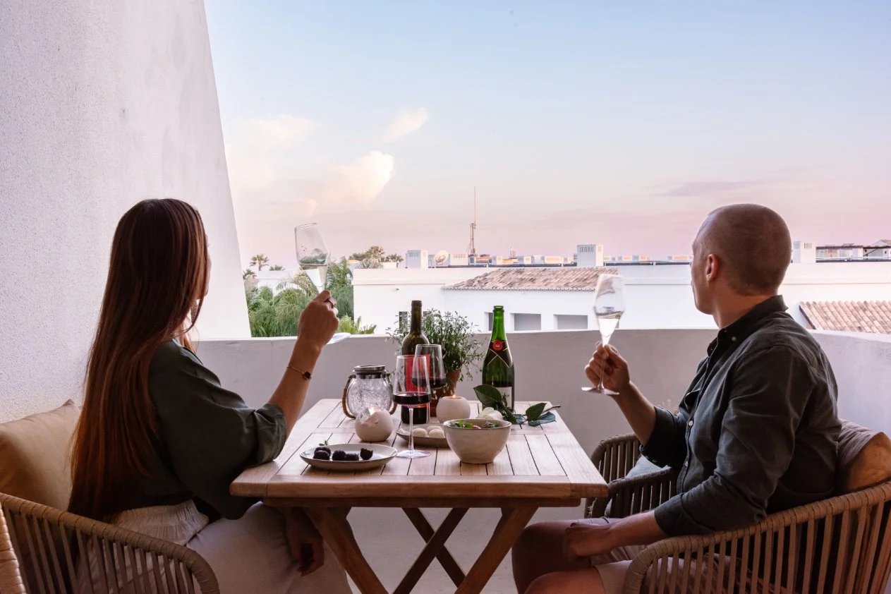 A man and a woman having drinks at an outdoor balcony table during sunset. Holiday home in Lagos Algarve