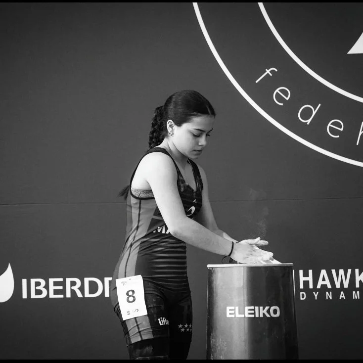 Joven atleta en uniforme de levantamiento de pesas lavándose las manos en un dispensador de gel.