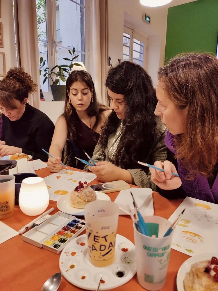 Groupe de femmes en train de peindre et de décorer des desserts, avec des peintures et des pinceaux sur une table