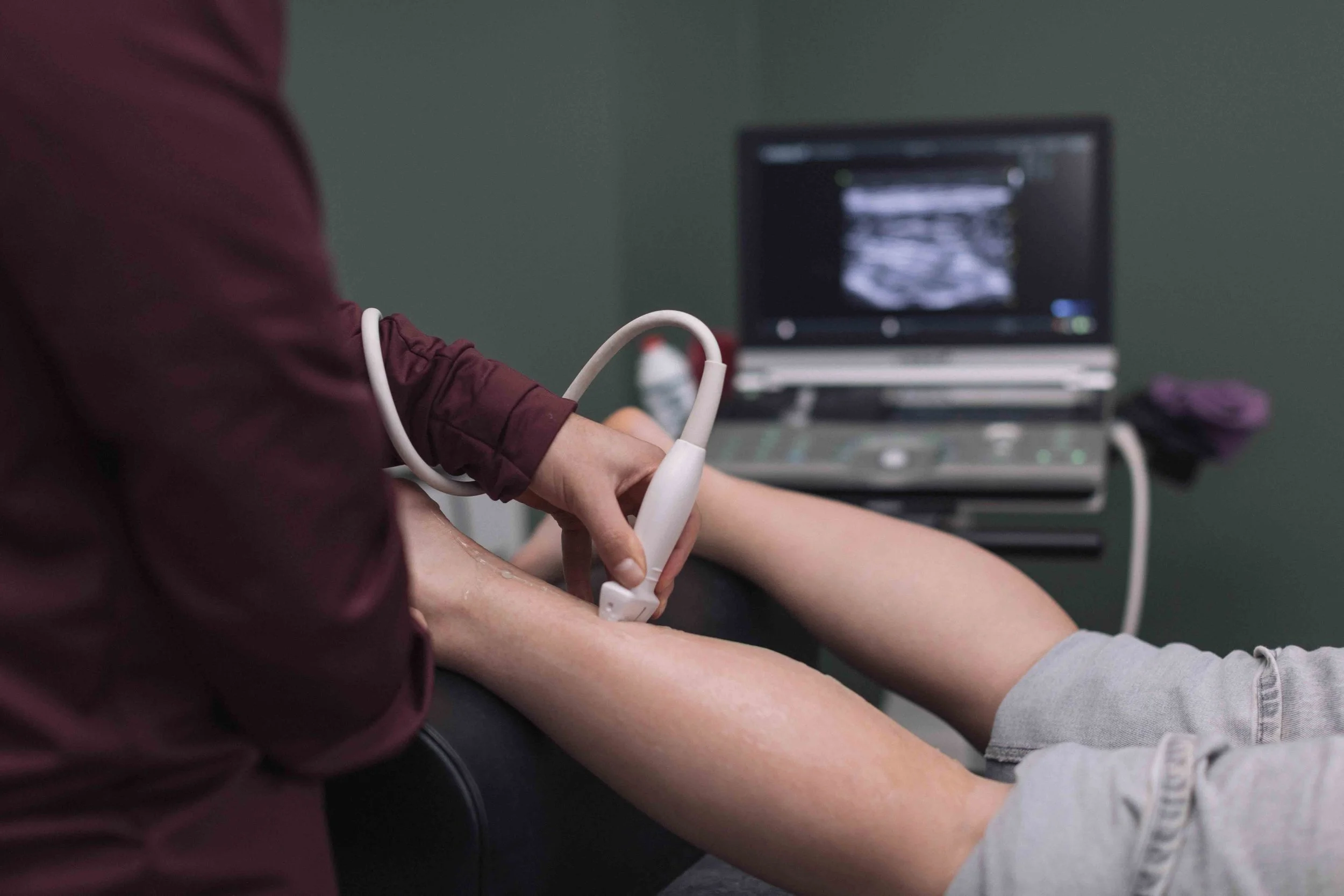 Goed Fysio Persoon die een arm uitlegt voor een onderzoek of medische procedure met een echoapparaat in een kliniek of ziekenhuis.