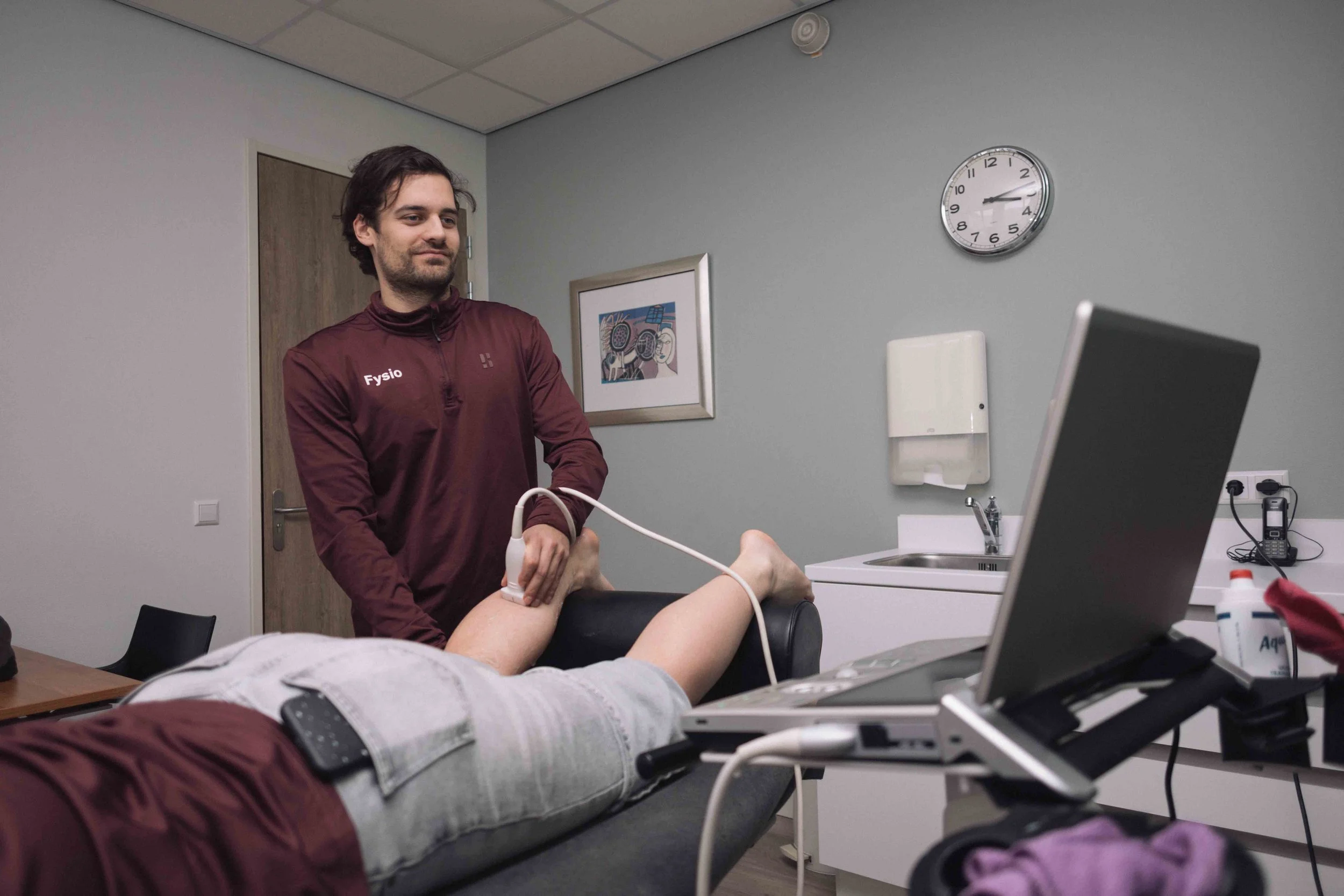 Goed Fysio Een medisch professional neemt een bloeddrukmeting op bij een patiënt die op een onderzoeksbank ligt in een dokterspraktijk of kliniek.