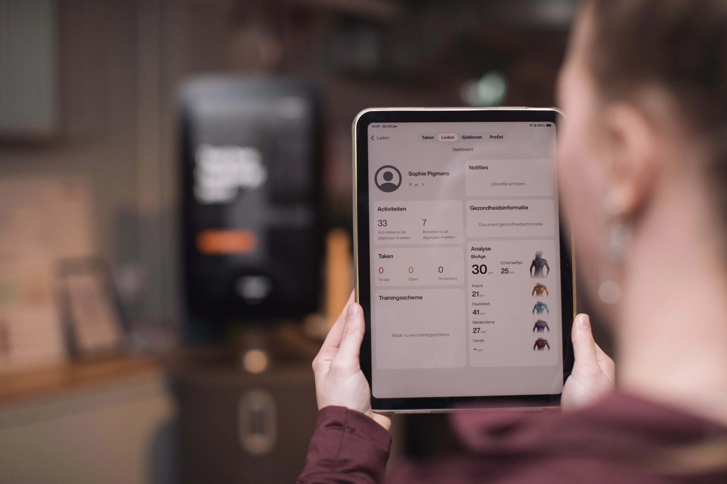 Goed Fysio Persoon houdt een smartphone met een fitness app open, waarin statistieken en gezondheidsinformatie zichtbaar zijn.