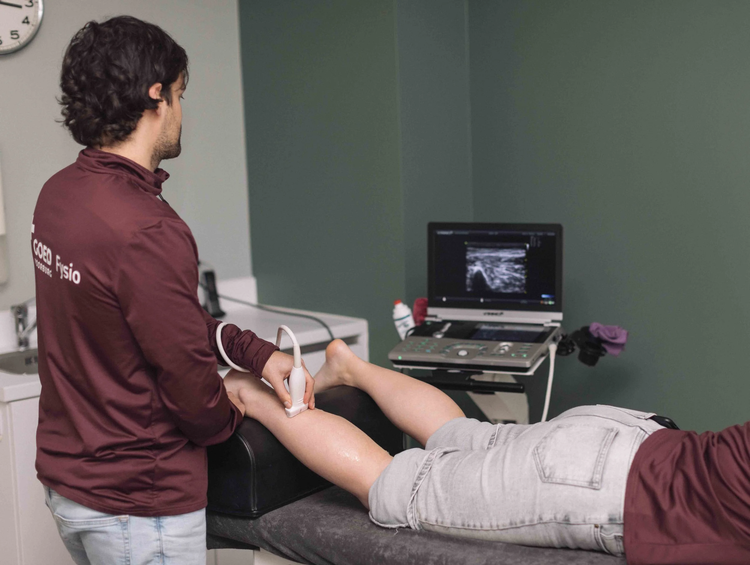 Goed Fysio Een medische professional voert een echografie uit op het onderbeen van een patiënt die op een onderzoeksbank ligt.
