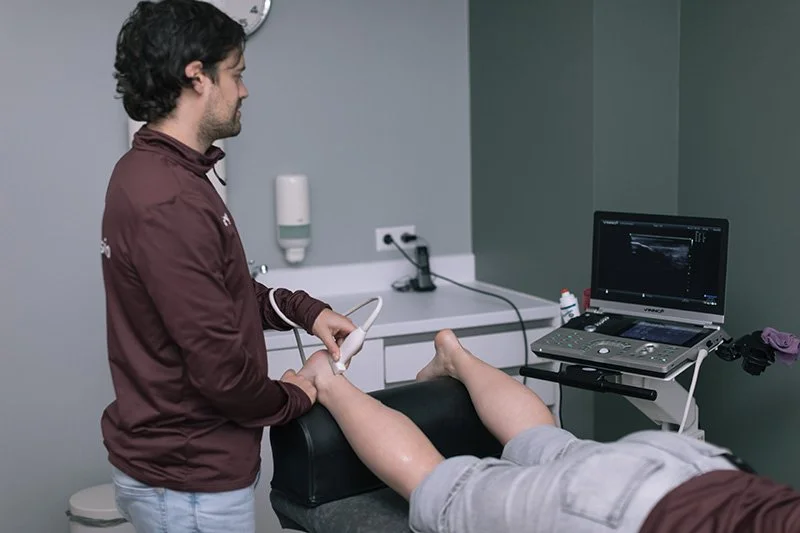 Goed Fysio Medewerker voert een echografie uit op een patiënt die op een medische tafel ligt in een kliniek of ziekenhuis.