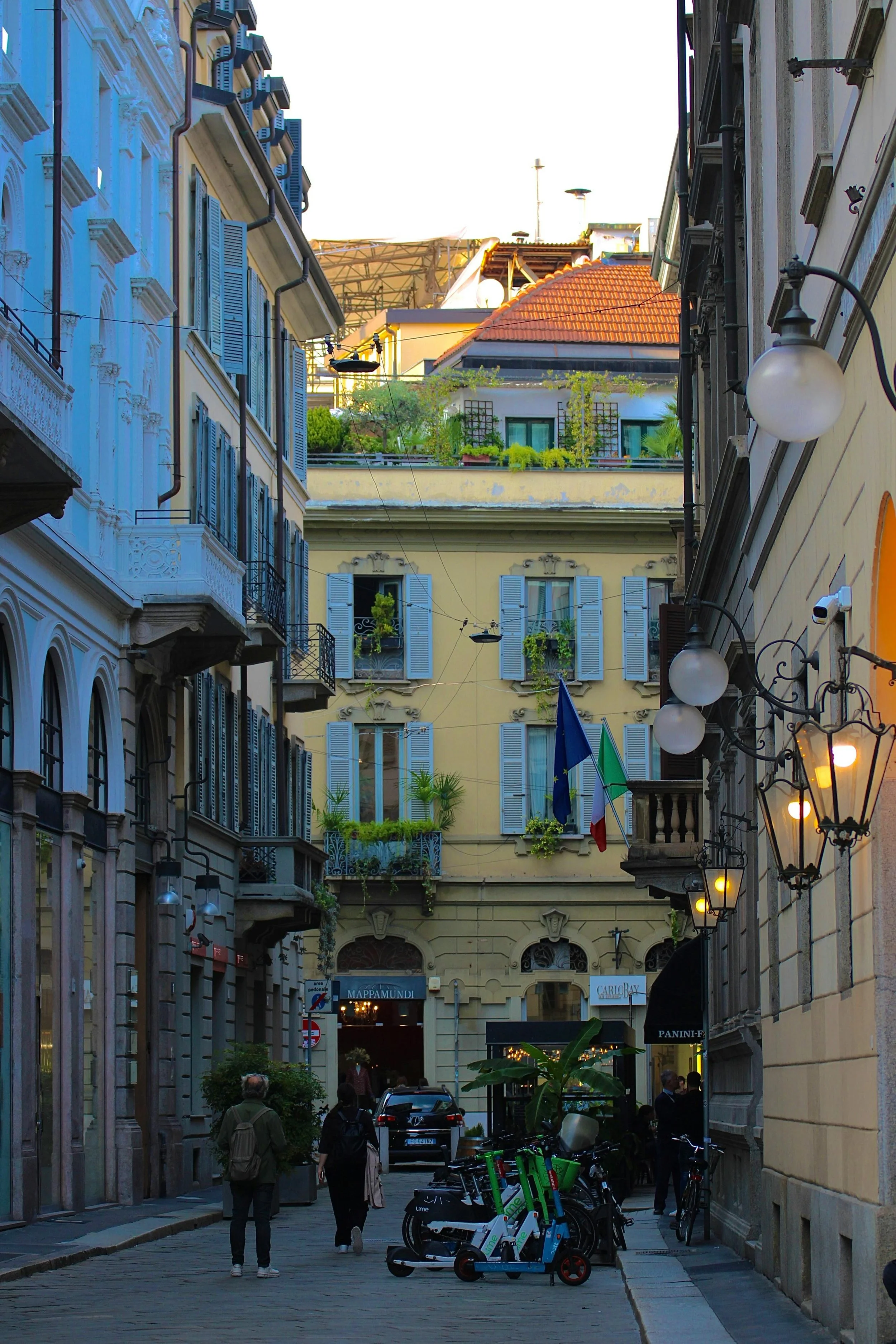 Situazione urbana con edifici storici, persone che camminano, biciclette, piante e bandiere di Francia e Unione Europea