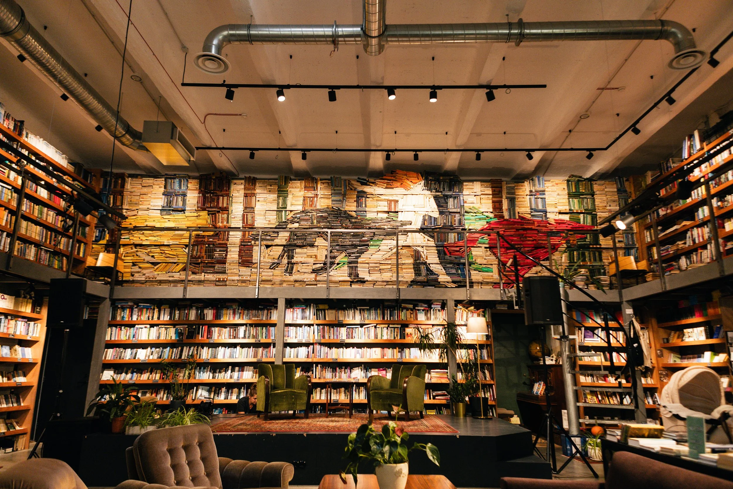 A bookstore or library interior with a large wall of books arranged to form a mural of a dog and a horse