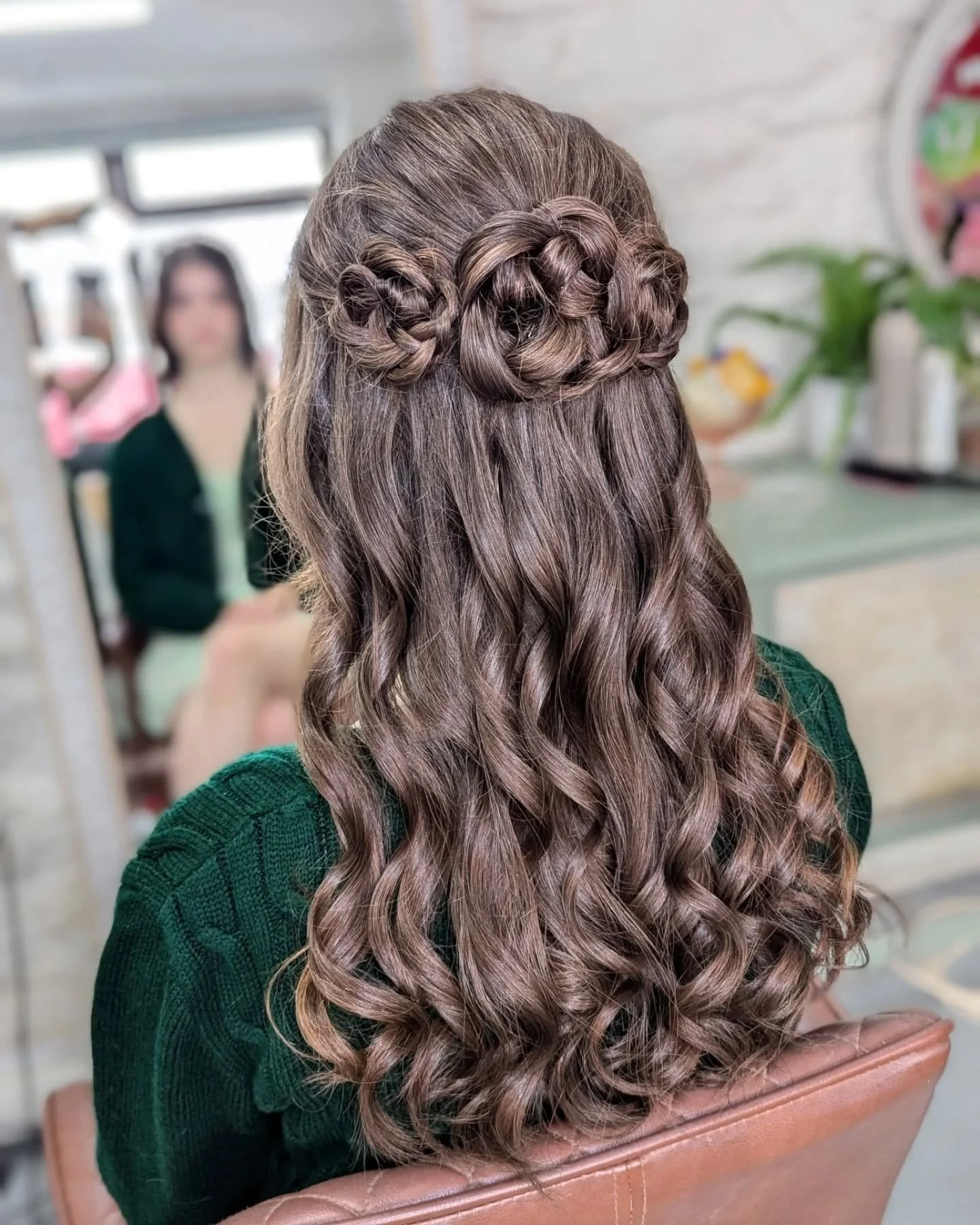 Back of a woman's head with long, brown, curly hair styled with a braided crown.
