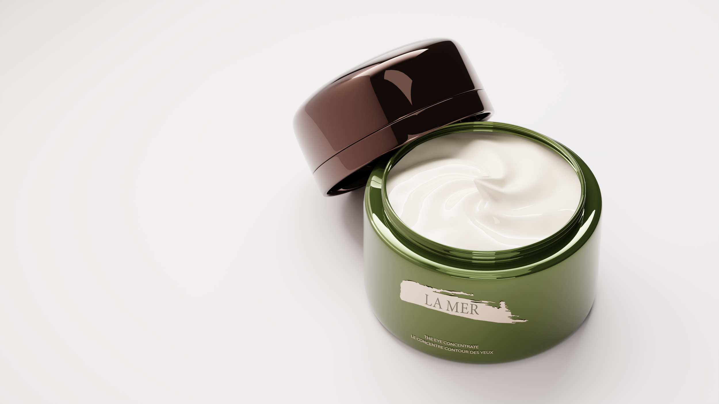 Open jar of La Mer eye concentrate cream with brown lid and white cream inside, placed on a white surface.