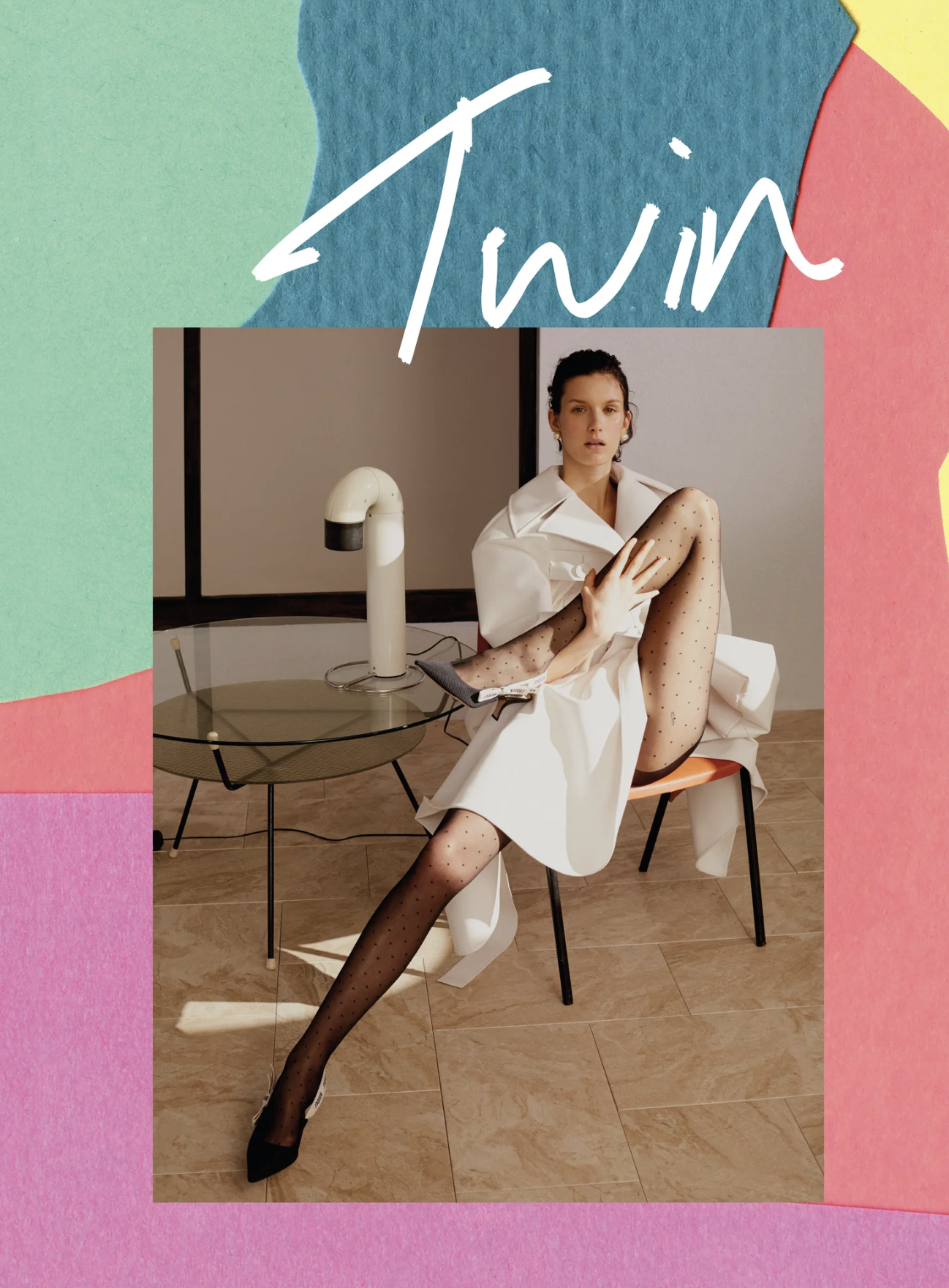 A woman in a white dress, black polka dot tights, and black heels sitting on an orange chair with one leg crossed over the other, in a room with a small round table, a white device on the table, and a beige wall background.
