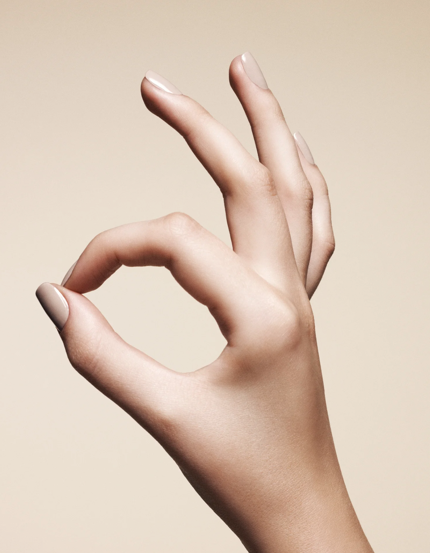 Close-up of a hand making an 'OK' gesture with the thumb and index finger forming a circle and the other fingers extended.