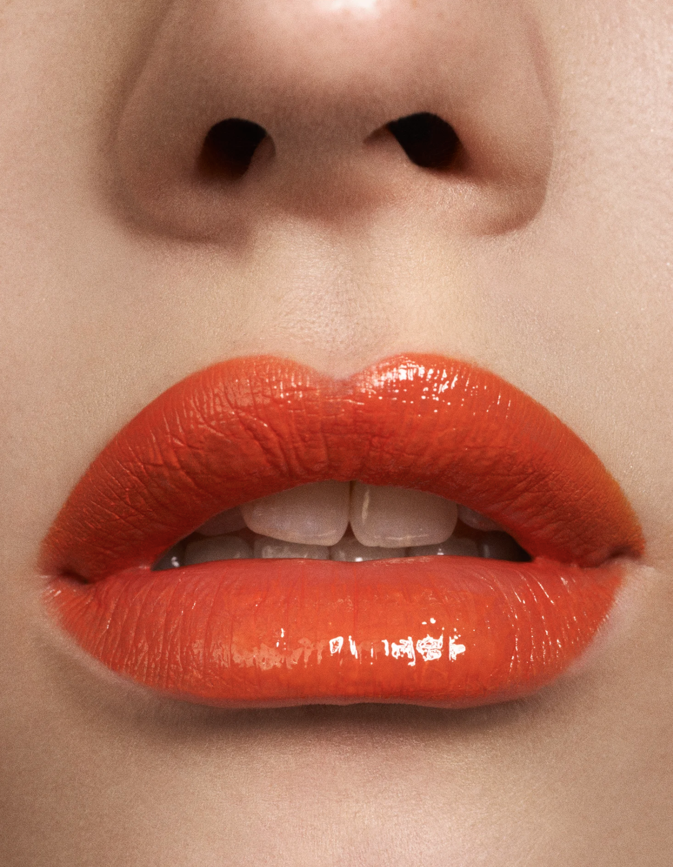 Close-up of lips with bright orange lipstick, part of a face including nose and teeth visible.