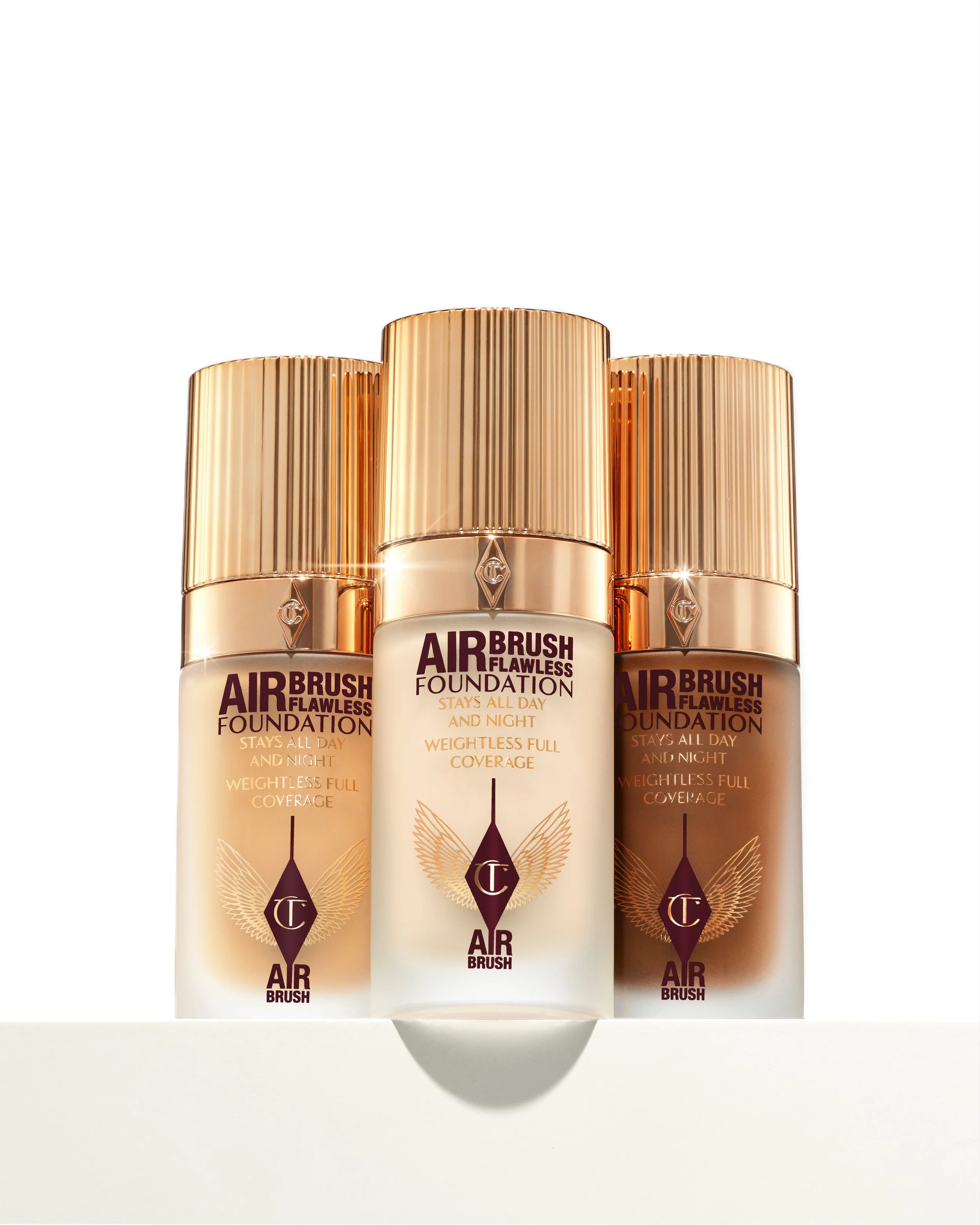 Three bottles of Air Brush Flawless Foundation in shades light to dark, standing upright on a white surface with a white background.