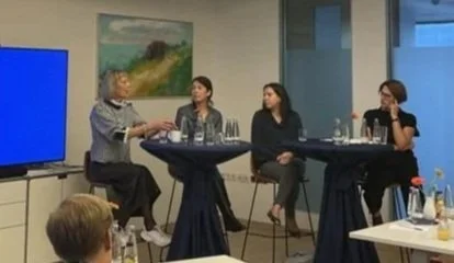 Gesprächsrunde mit mehreren Teilnehmerinnen in einem Konferenzraum im Austausch zu KI, Gesundheit und gesellschaftlichen Fragen.