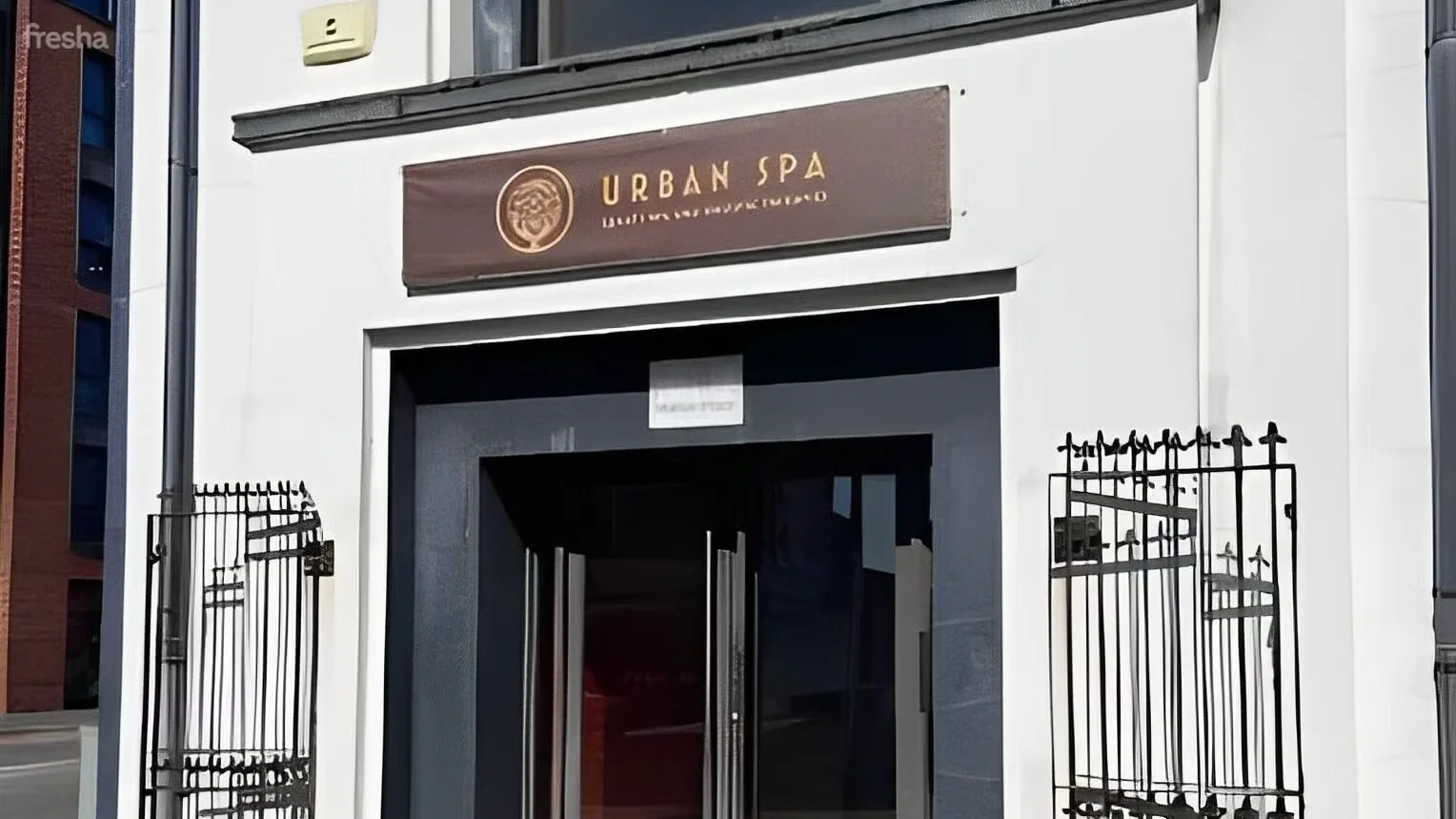 Exterior view of a building with a sign reading 'Urban Spa' and decorative iron gates on either side of the entrance.