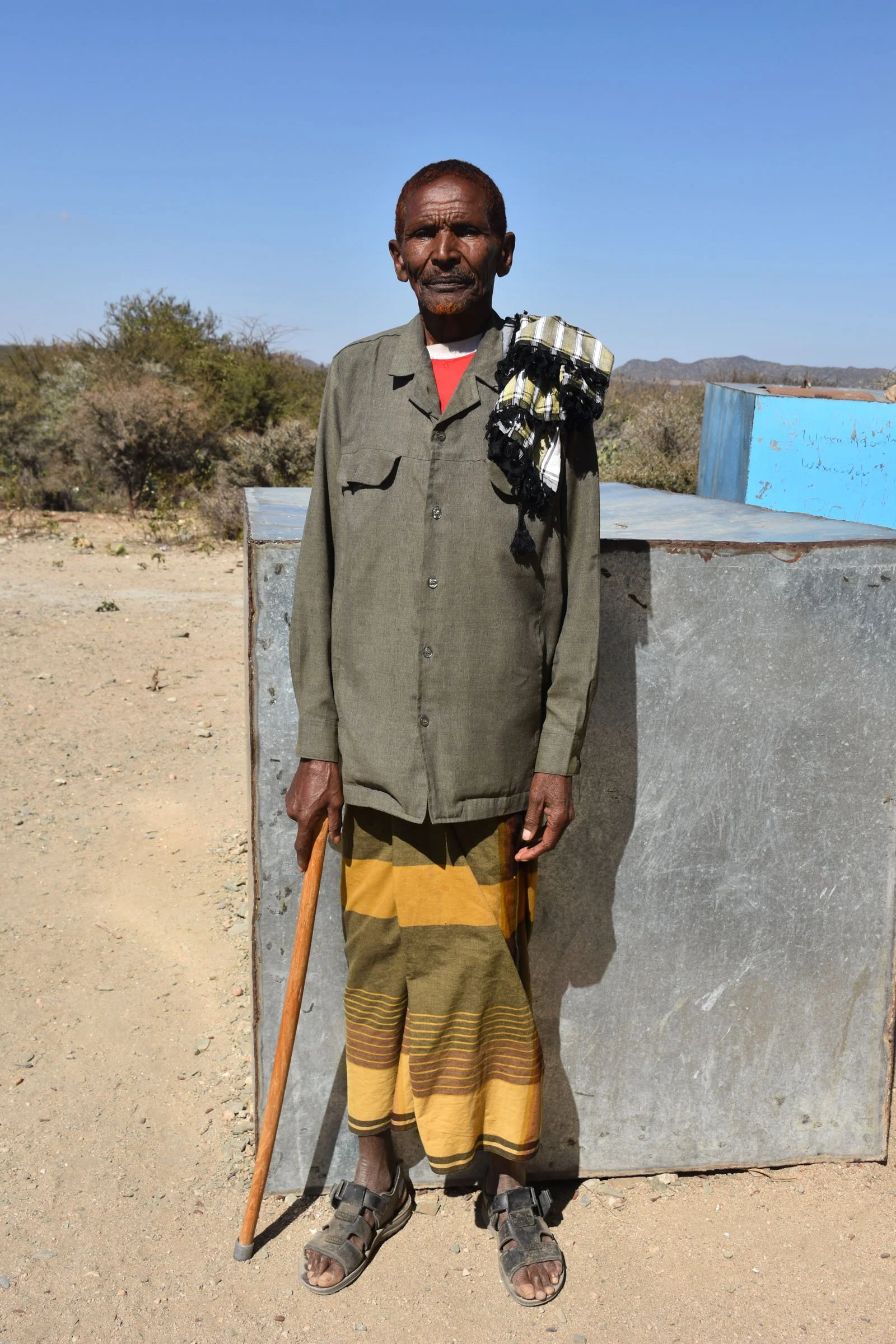 A man stands for a portrait while leaning on a stick