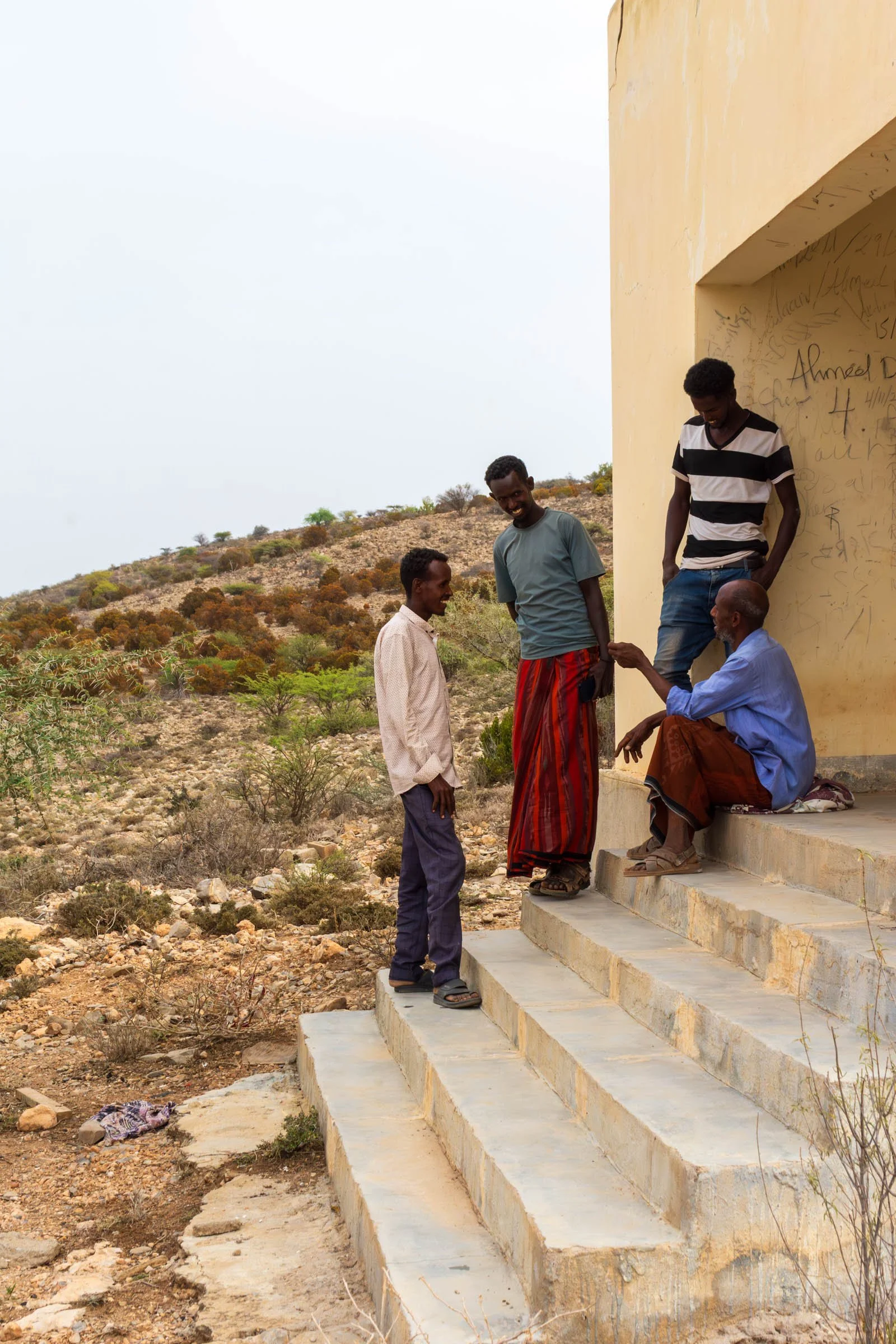 A group of men stand and sit on steps talking to each other