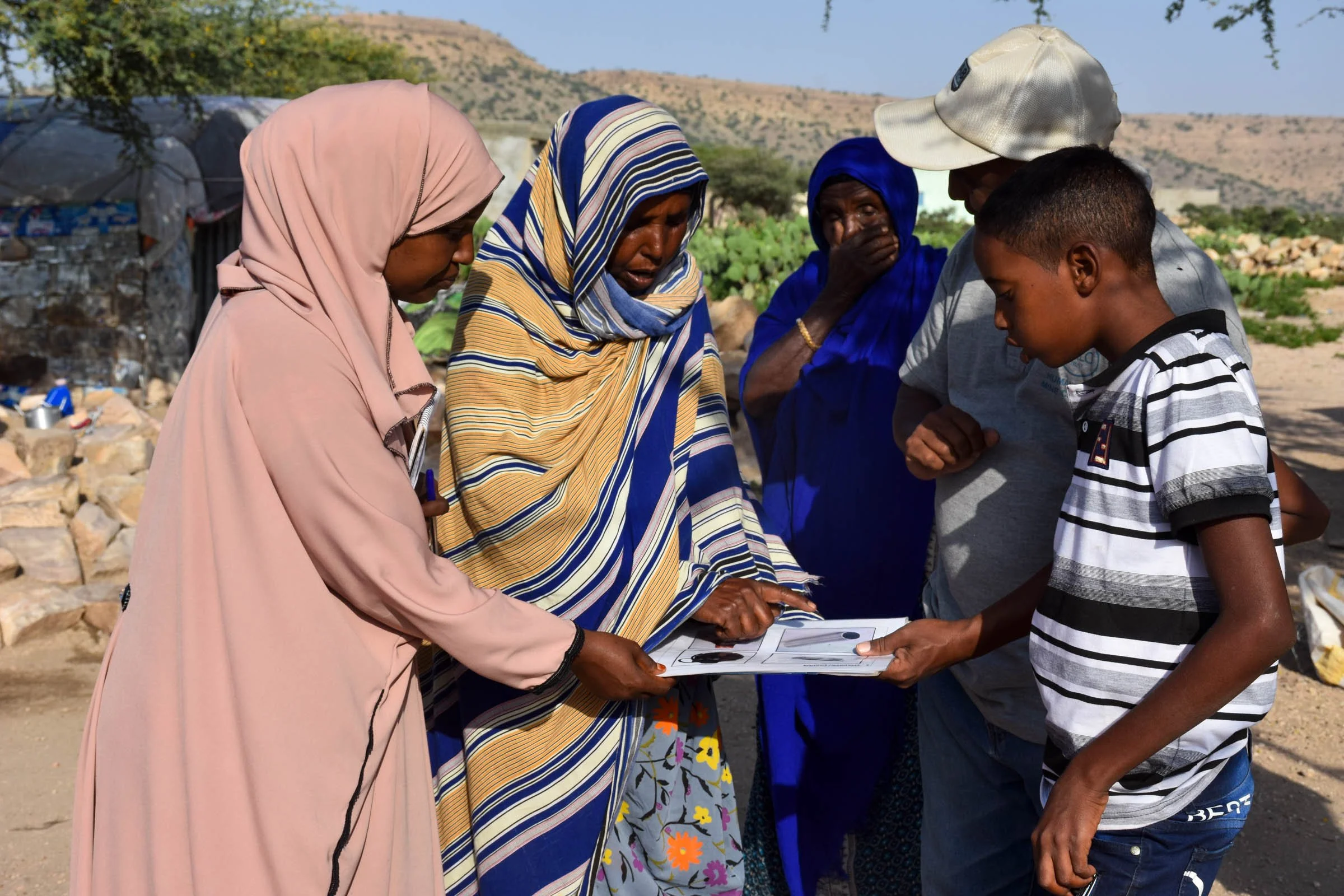 A group of people examine a card of image, as a woman point to one image