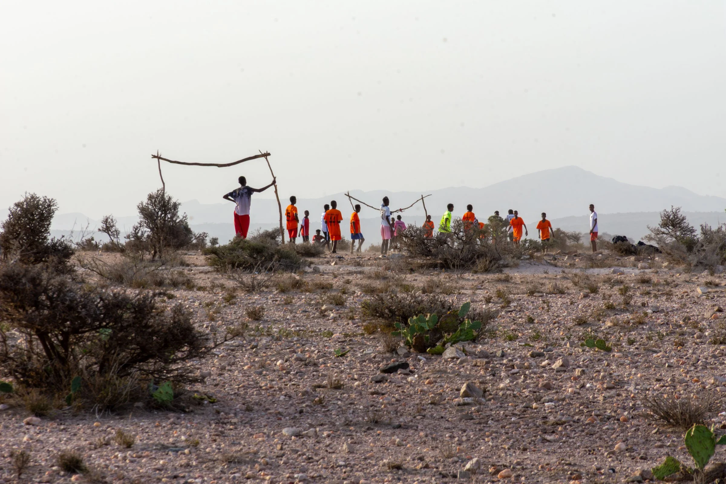 A group of adolescent boys play football in the foothills of mountains
