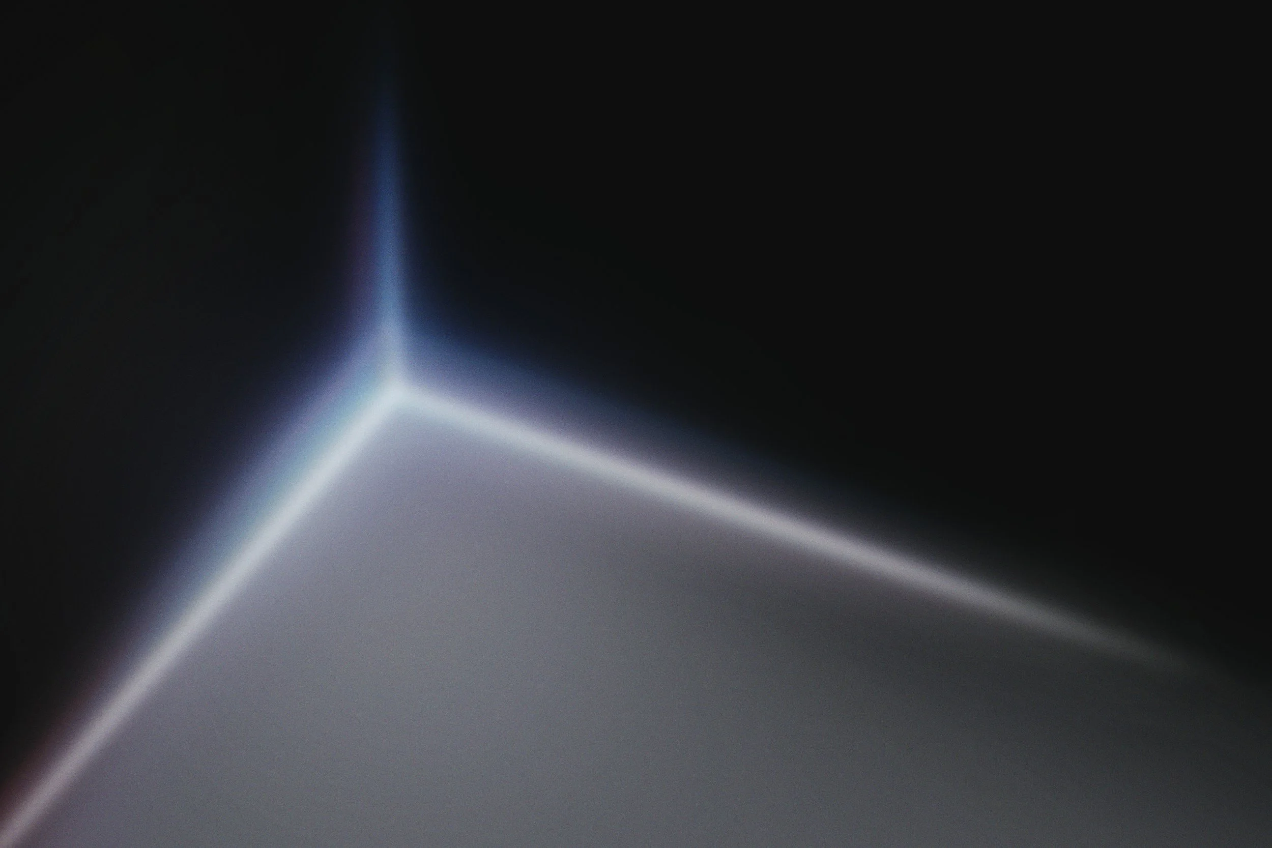 Close-up of a glowing triangular shape with light reflections and shadows against a dark background.