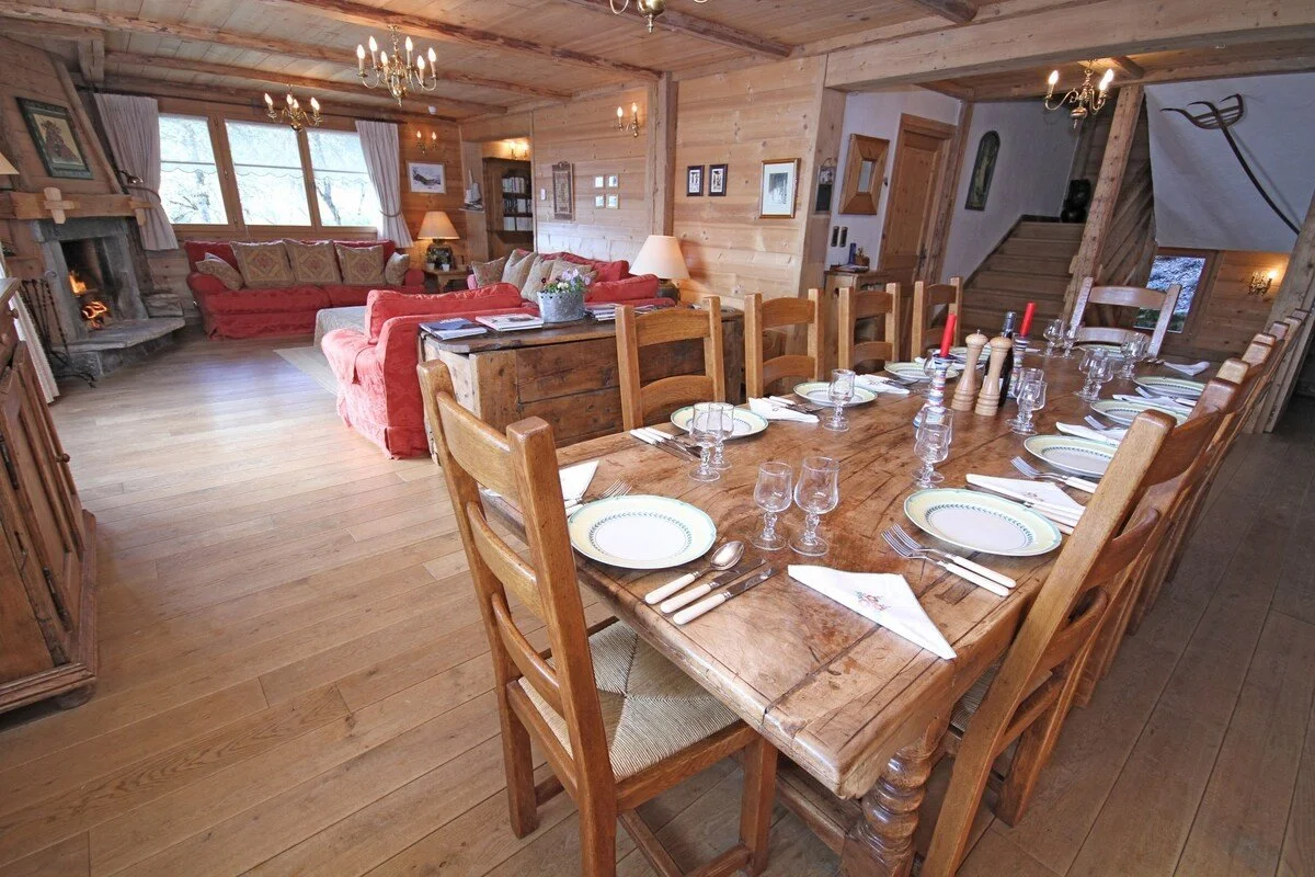Cozy living room with wooden walls and ceiling, red sofas, a fireplace, a coffee table, and various decorative items.