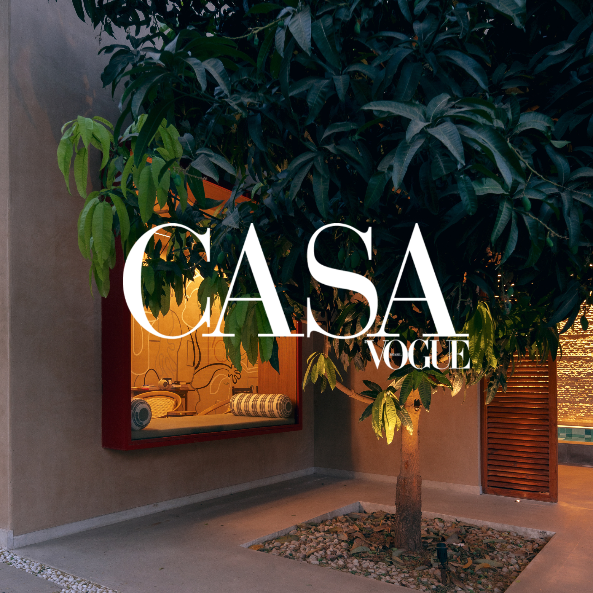 A large indoor plant with broad green leaves grows next to a wall with a window display of a turntable and books. The window has a red frame. The words 'Casa Vogue' are overlaid on the image.