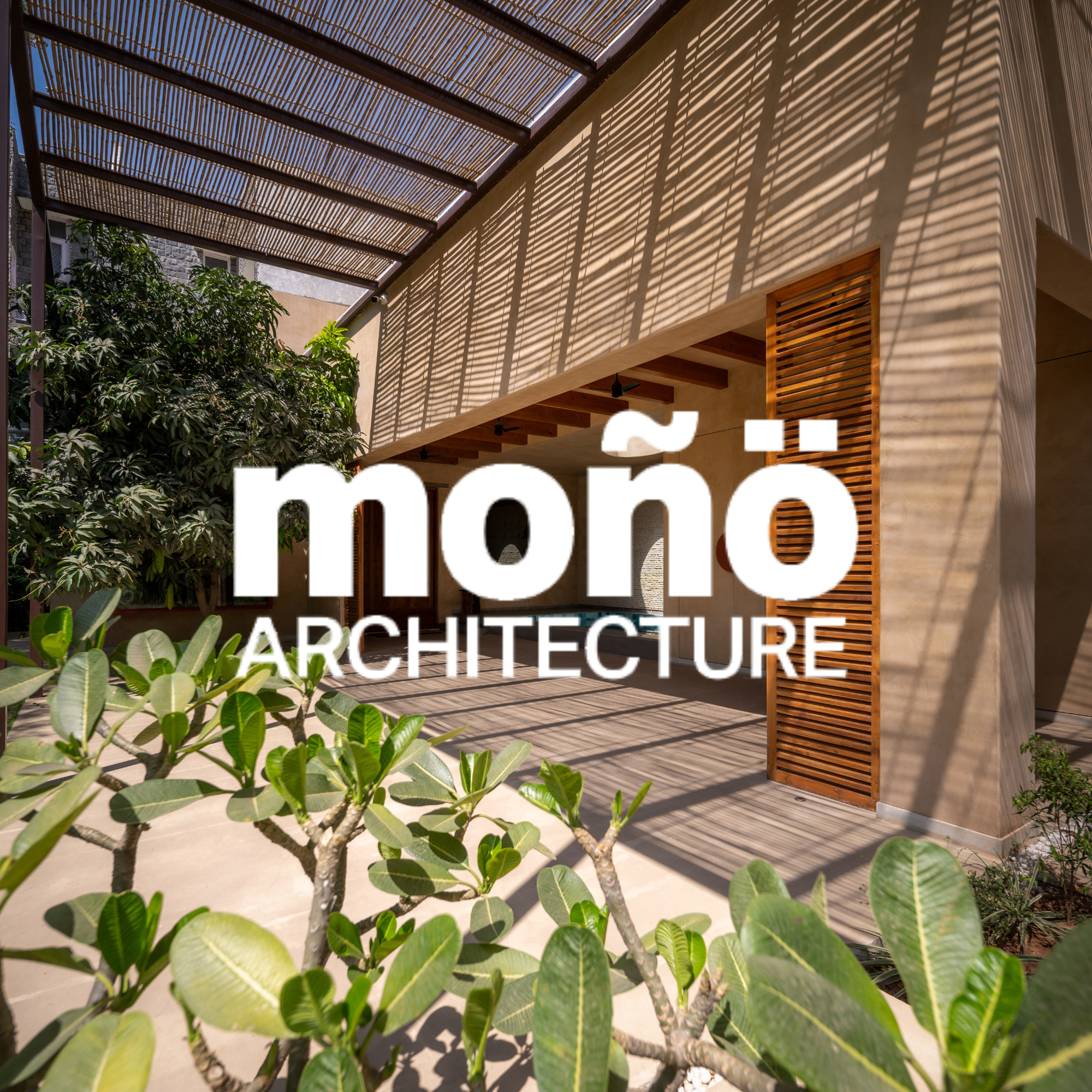 Modern house with wooden slatted roof casting shadows, greenery in foreground, and a wall with wooden accents.