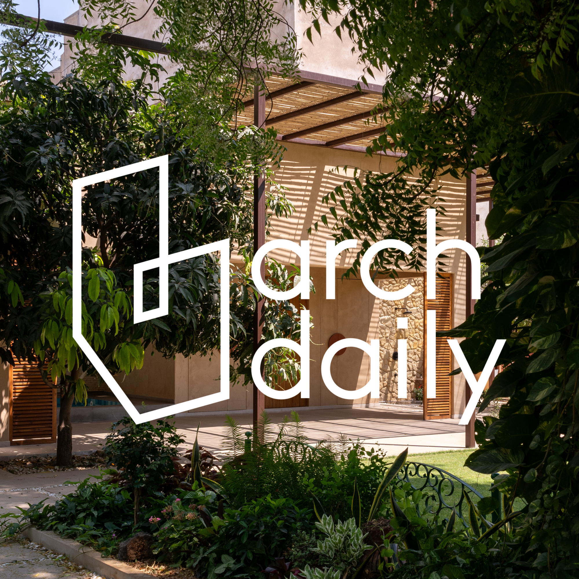 A lush garden with plants and trees surrounding a modern outdoor patio area with a pergola and stone wall, logo overlay reading 'arch daily'.