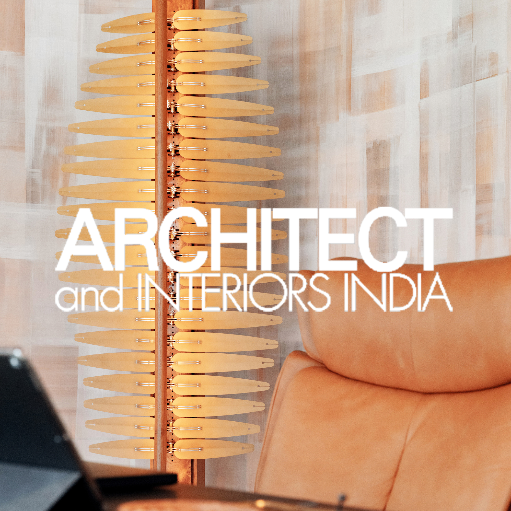 Interior of an architecture magazine showing a wooden sculpture, a tan leather chair, and a blurred object in the foreground.