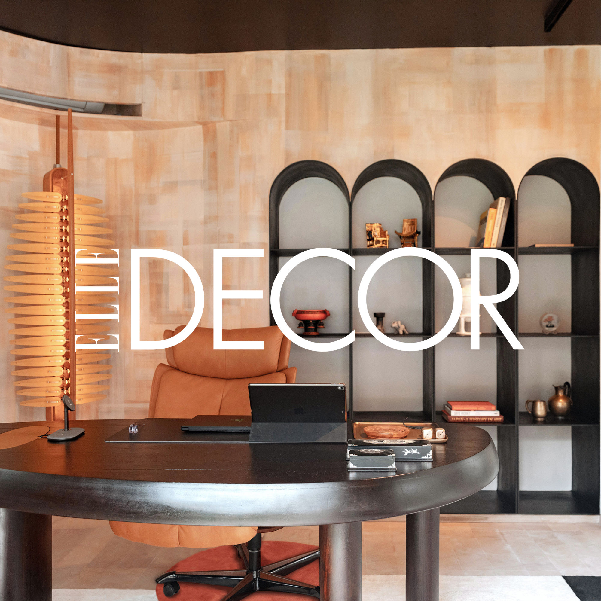 Modern office with a curved black desk, leather chair, decorative shelving with books and artifacts, and warm lighting.