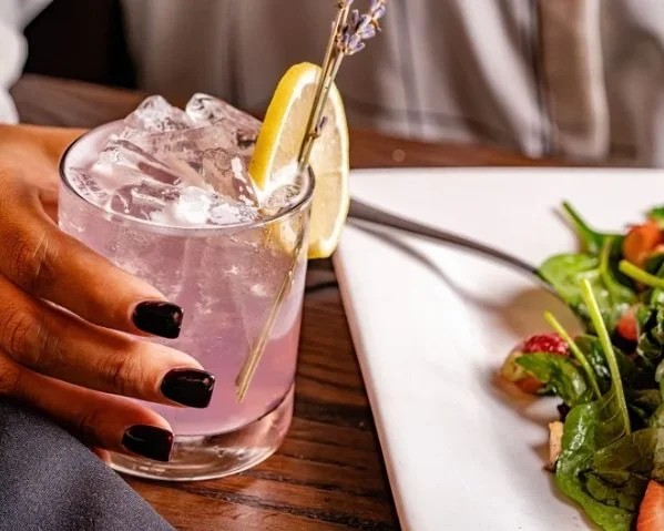 A woman's hand delicately holds a glass of refreshing drink, creating a vibrant and enticing image.