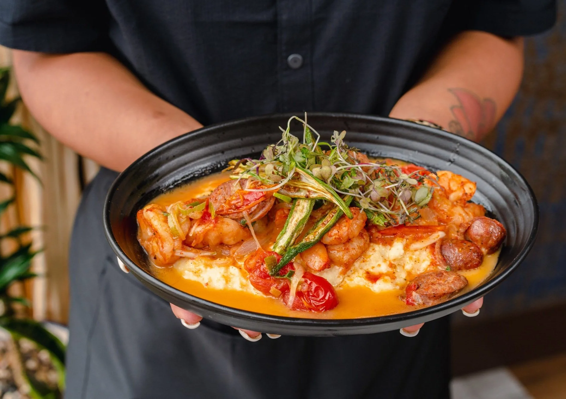 A person holding award winning Shrimp & Grits dish plate.