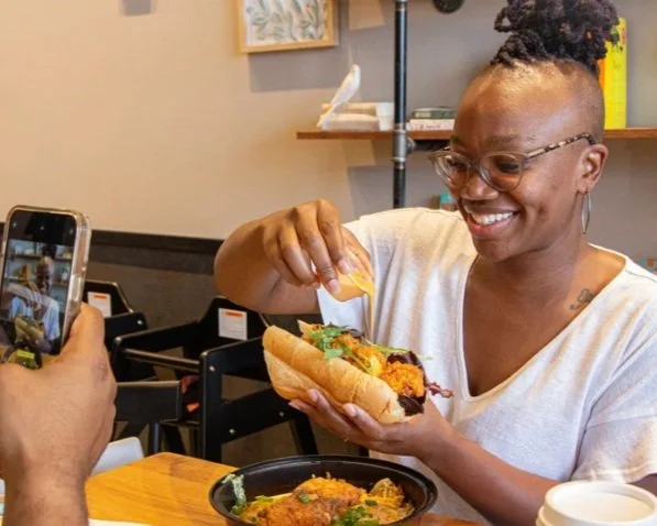 A man capturing a photo of friend's delicious meal using a phone.