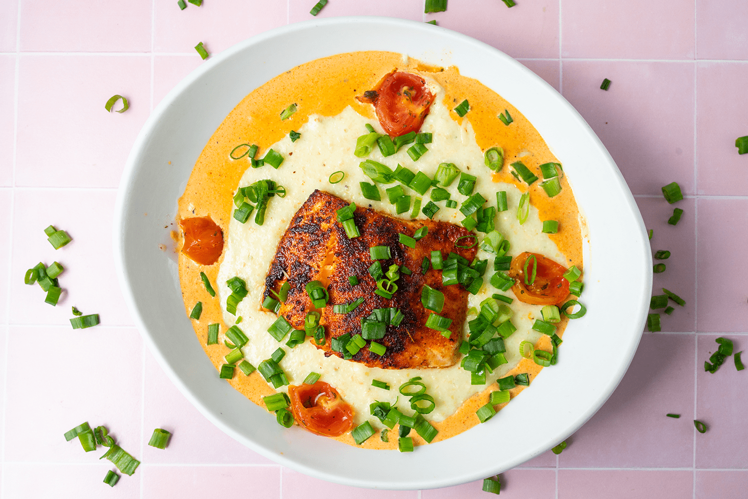 Blackened fish over creamy grits topped with green onions.