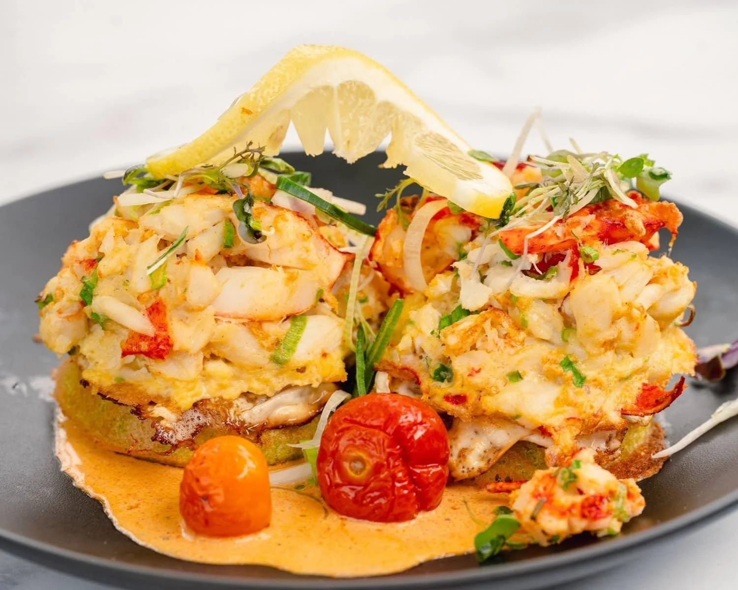 Two stuffed potatoes topped with lobster and tomato sauce, served on a plate.