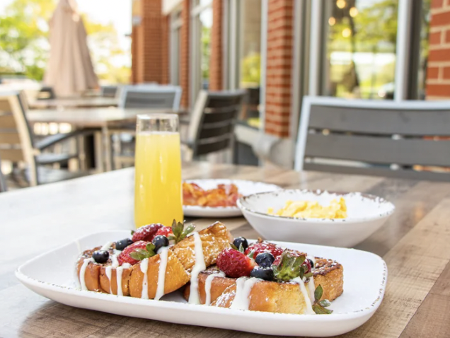 French toast with berries, cream drizzle, and orange juice.