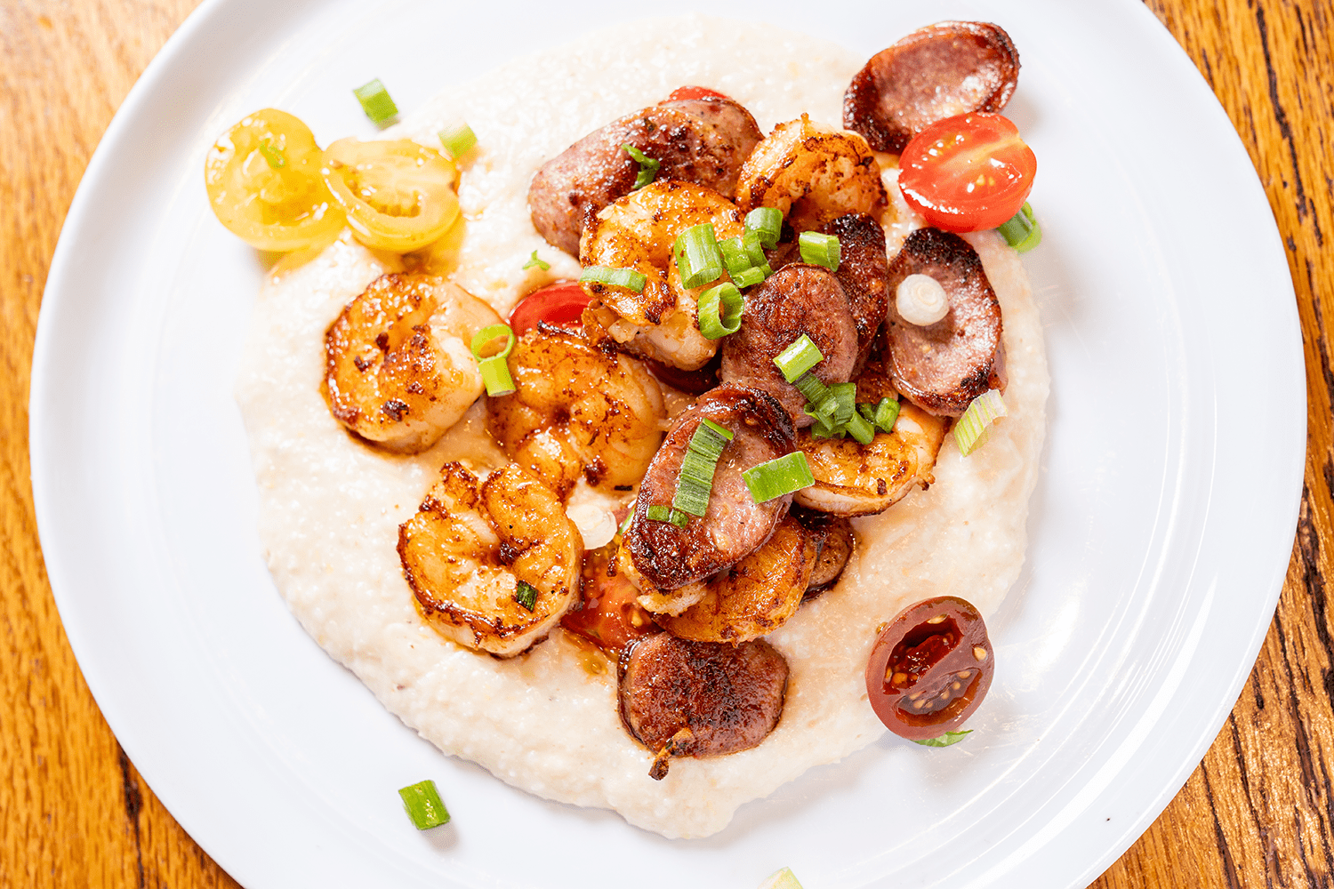 Shrimp and sausage over creamy grits with tomatoes and scallions.