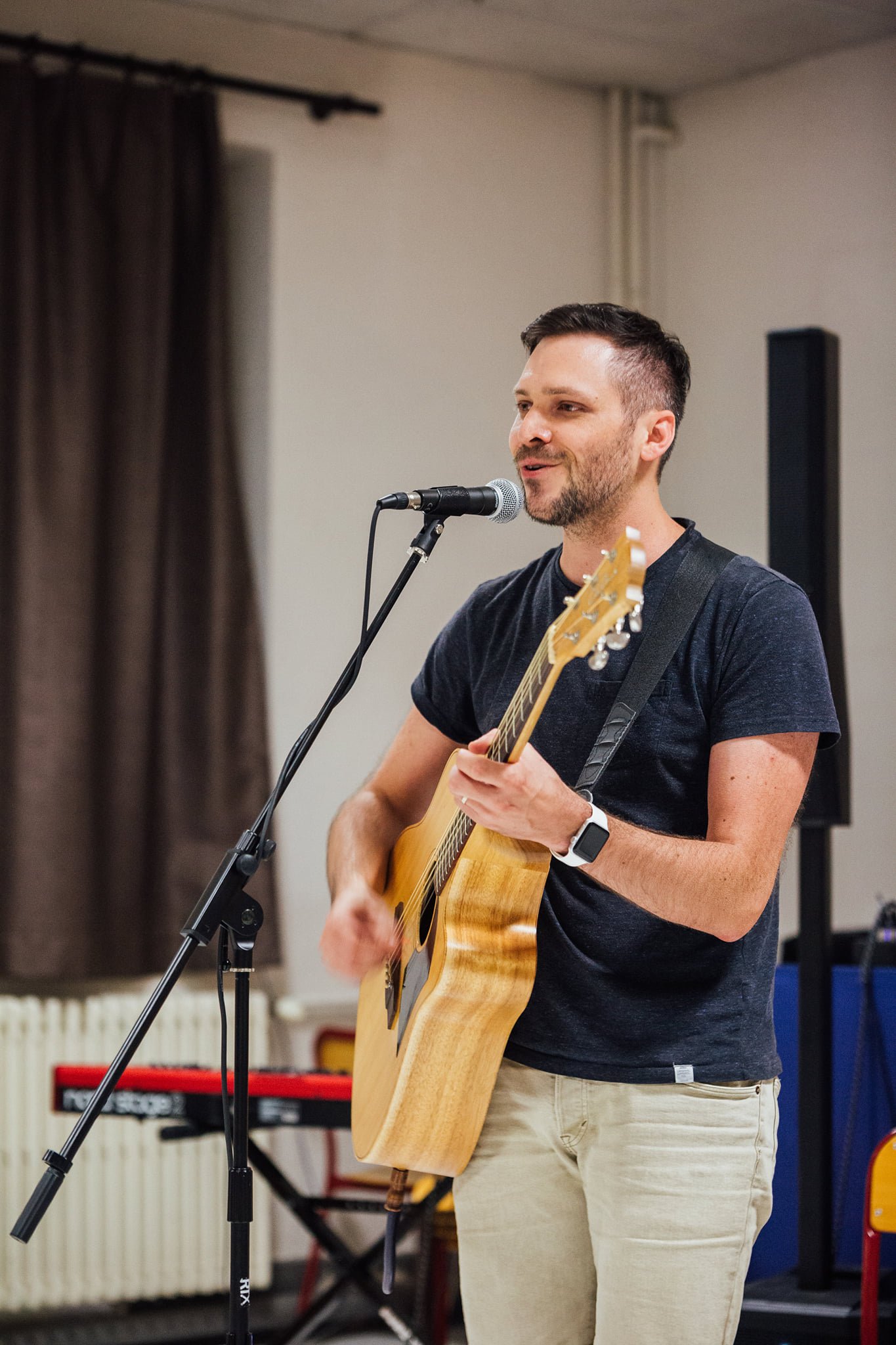 Homme jouant de la guitare et chantant devant un microphone dans une pièce