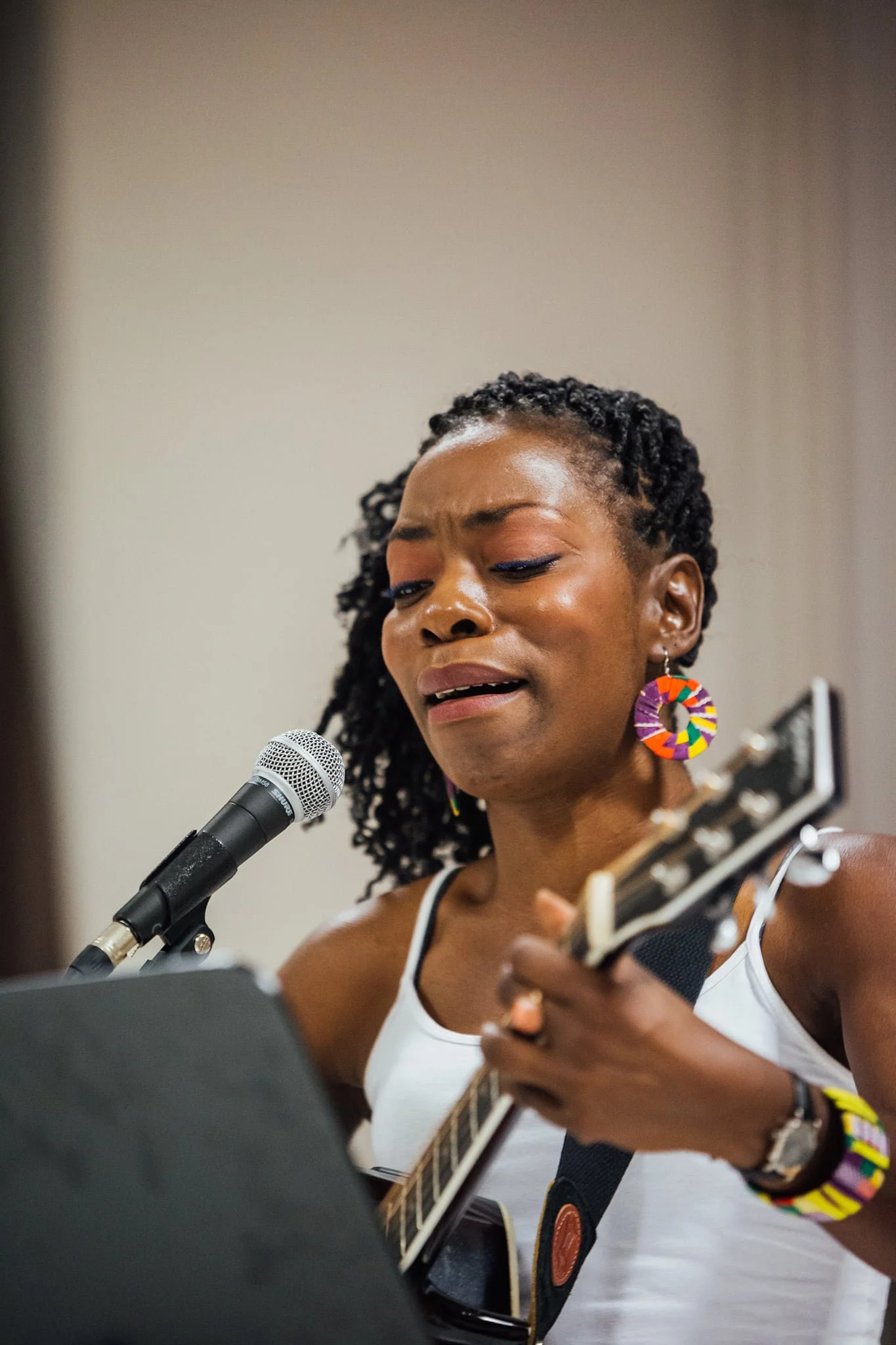 Une femme chante en jouant de la guitare et en utilisant un microphone.