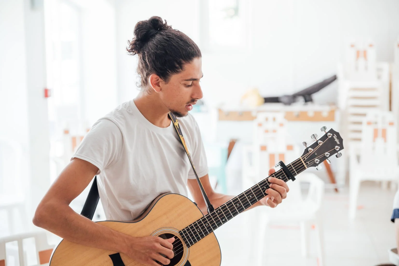 Un jeune homme joue de la guitare acoustique dans une pièce lumineuse.