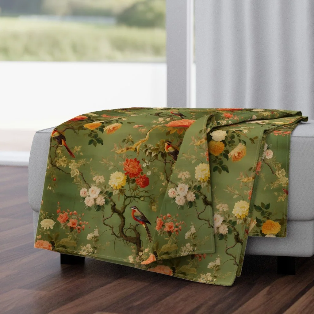 A green floral tablecloth with a bird and flower pattern draped over the edge of a white sofa.