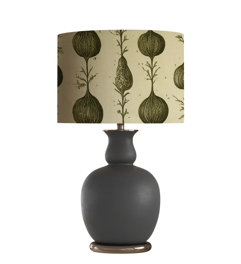 A table lamp with a dark gray ceramic base and a fabric lampshade featuring a green botanical pattern of stylized onion or bulb-like shapes.