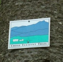 Trail sign for Cross Vermont Trail attached to a tree trunk.