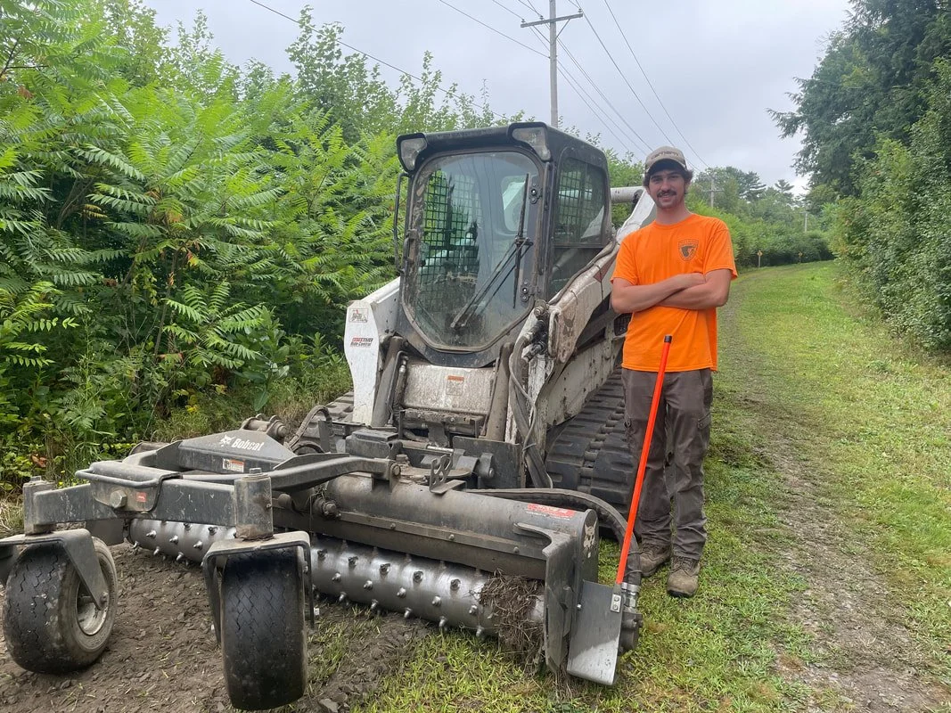 That's Hi-Vis Hunter of the NH Bureau of Trails with the Harley Rake. The carbide points on the roller grind up the grass and roots along with stirring up the rocks. Hunter used this to prepare the trail for grading. It was a hot and dusty job but Hu