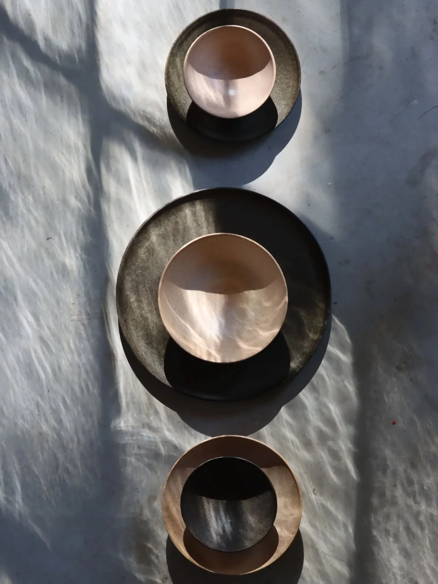 A composition of plates and bowls glazed in black and apricot.

The light pouring through the window reminds of ripples on water. Photographing the finished ceramics is always a joy and a reward after all the steps and work that led to this point.
.
