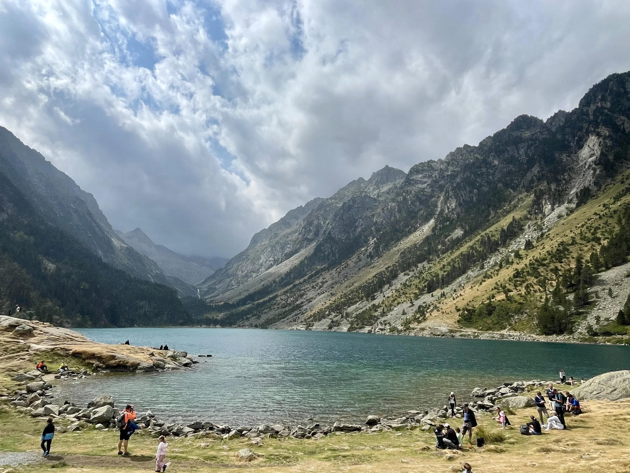 Hikers resting around Lac de Gaube, a relatively easily accessible alpine lake surrounded by mountains and reachable from the Pont d'Espagne.