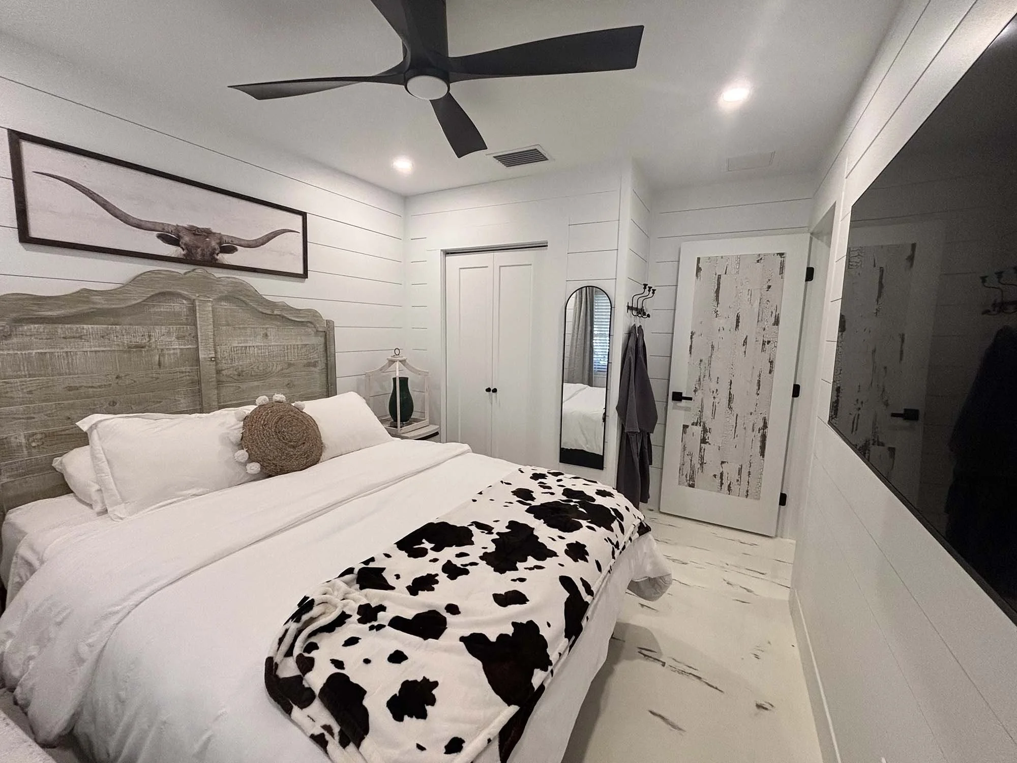 Quiet, clean bedroom with white linens and a cow print blanket