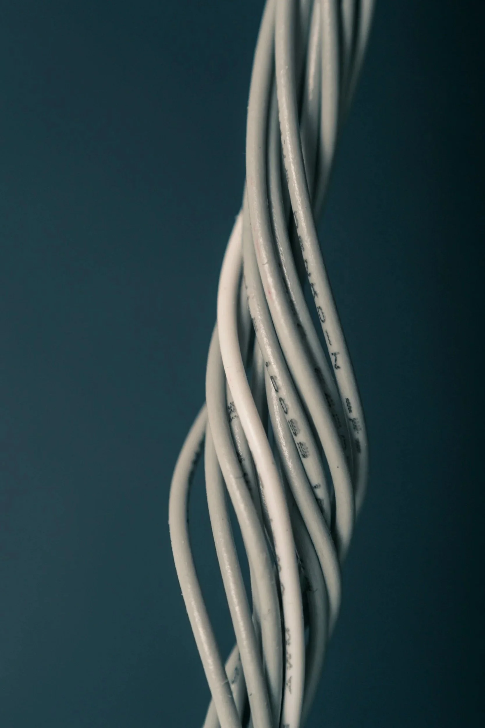 Close-up of white twisted electrical wires against a dark background.